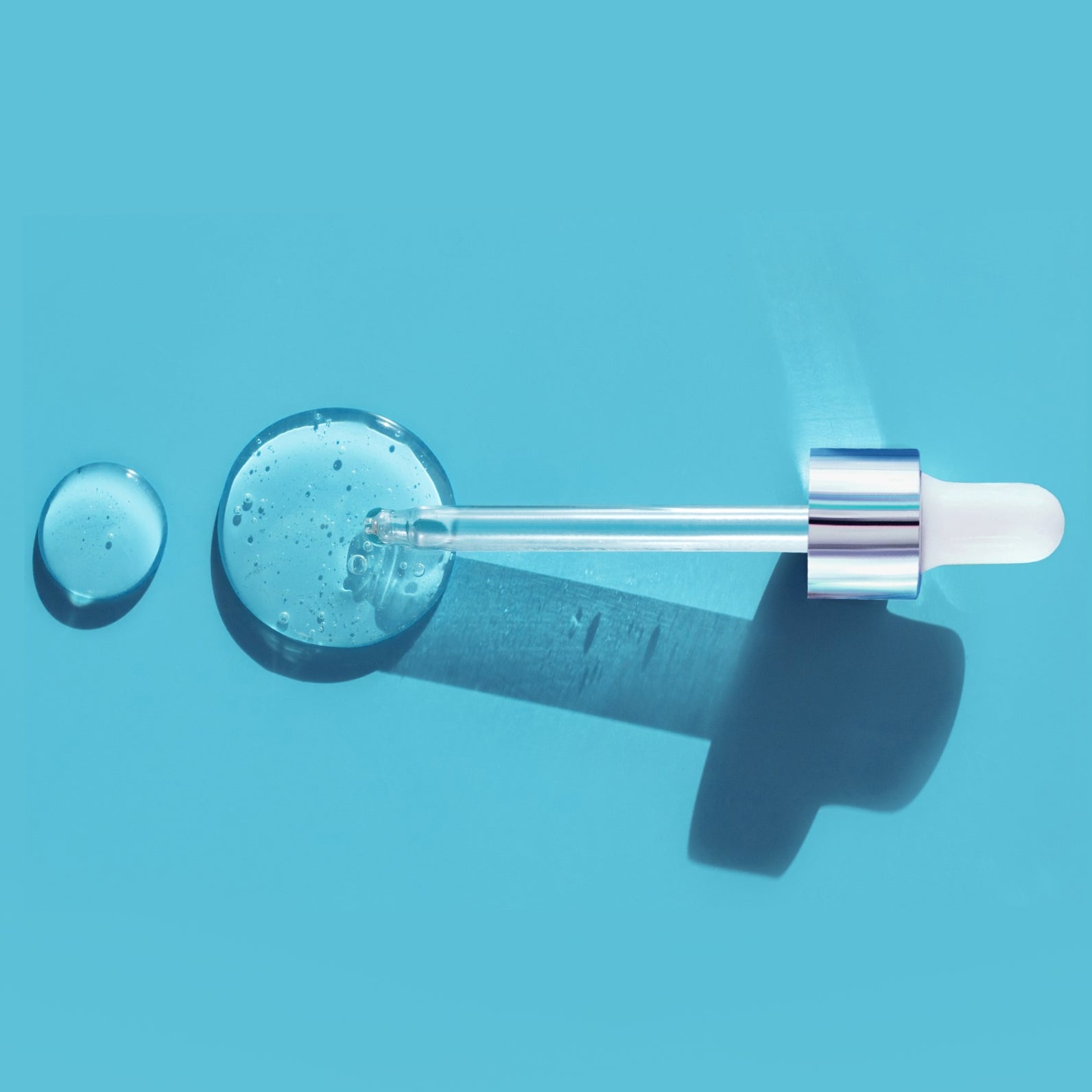 A dropper of hyaluronic acid rests on a blue background. Image Credit: Ekaterina Klishevnik