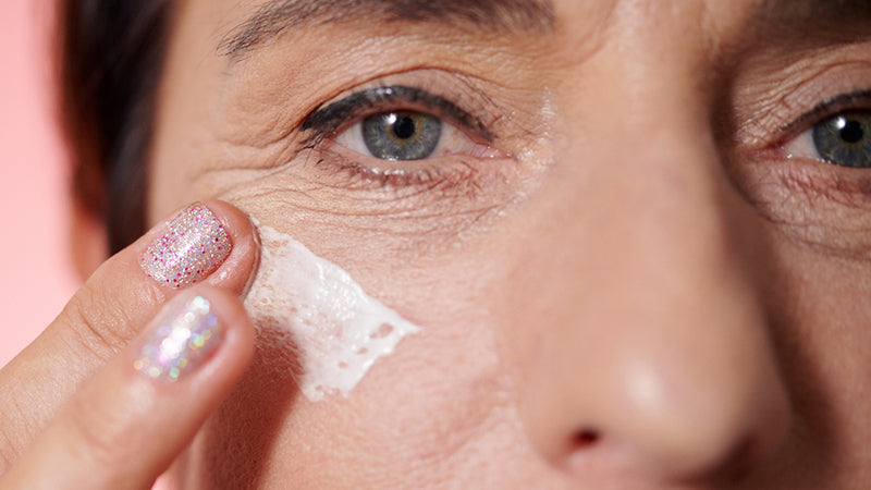 Closeup on a woman applying eye cream under her eyes.