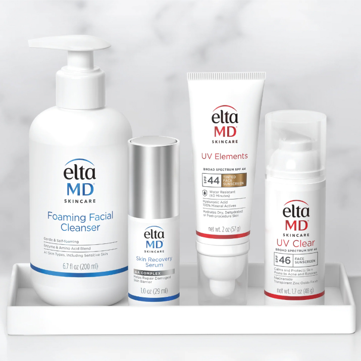 Four EltaMD products (foaming face cleanser, skin recovery serum, UV Elements tinted sunscreen, and UV Clear sunscreen) in a white tray against a white and grey marble background