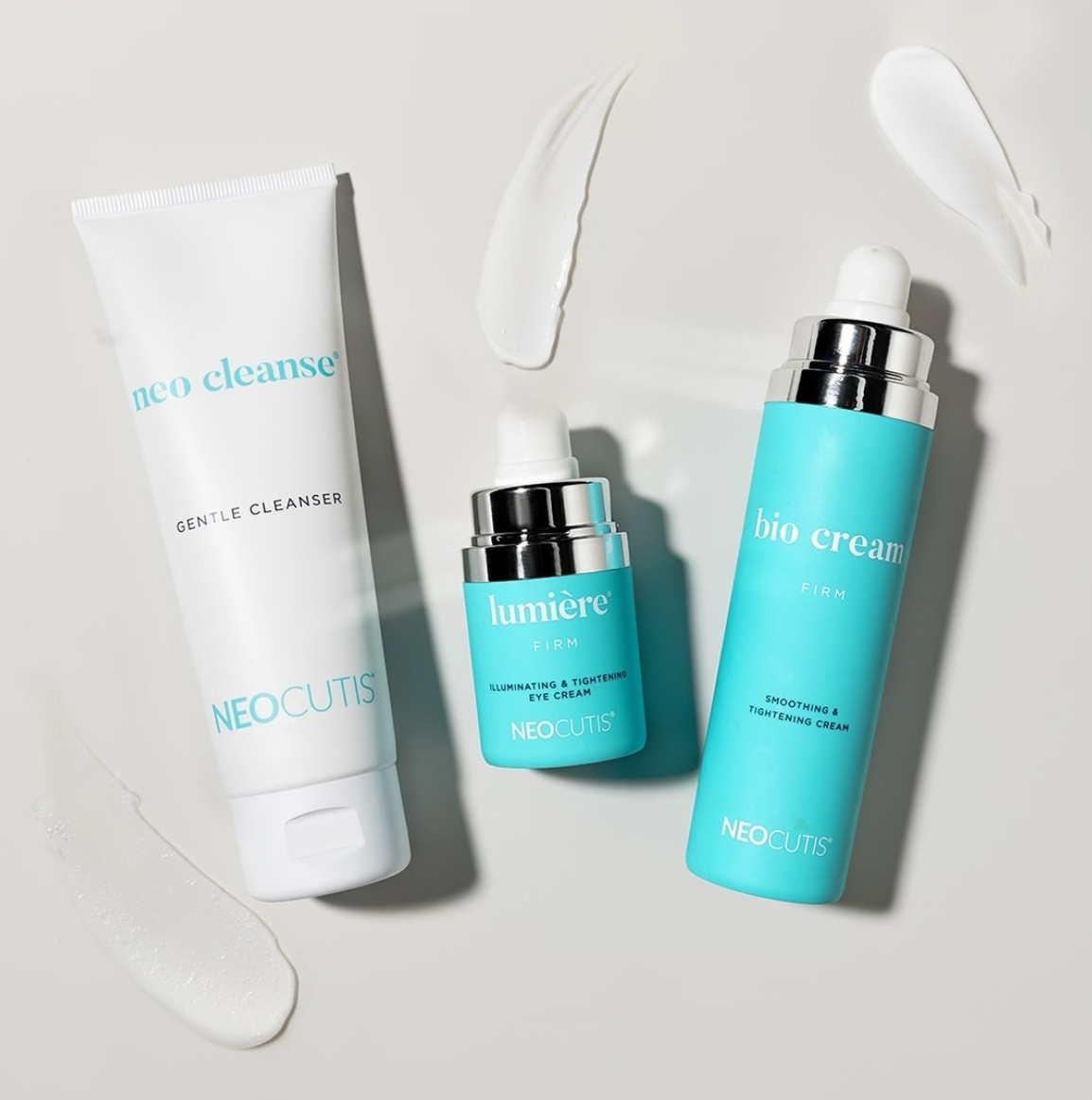 Three Neocutis products in turquoise and white lay on a light grey background with swatches of each product pumped out near them