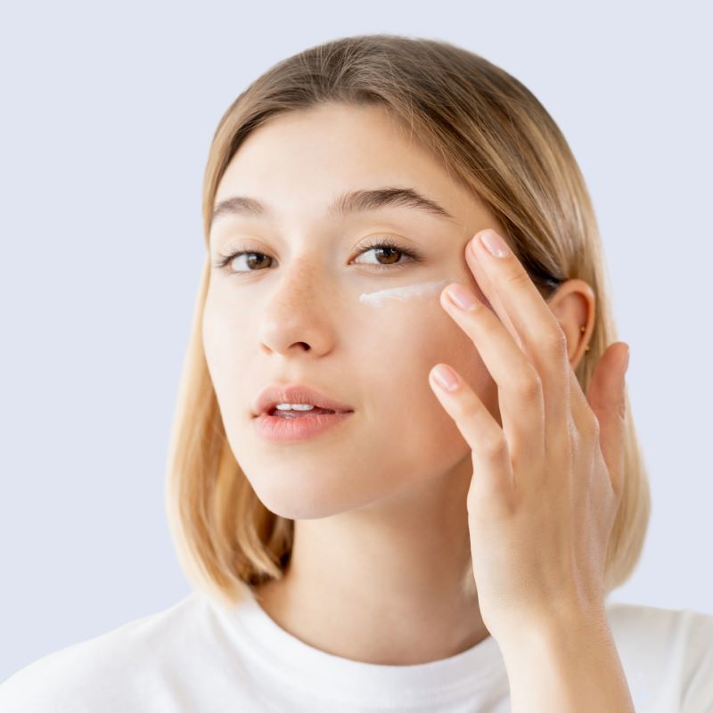 Woman applying a white cream under her eyes.