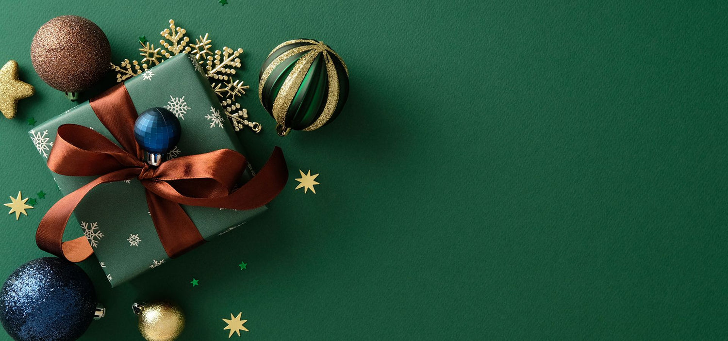 Gift box with a red ribbon and glittery ornaments on a green background