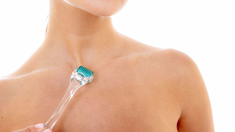 Closeup on a woman using a microneedling roller on her chest