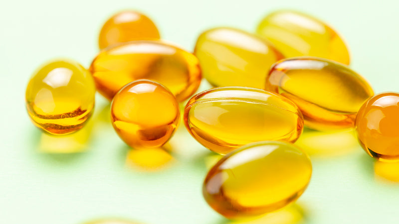 Several Vitamin E capsules on a pale green background