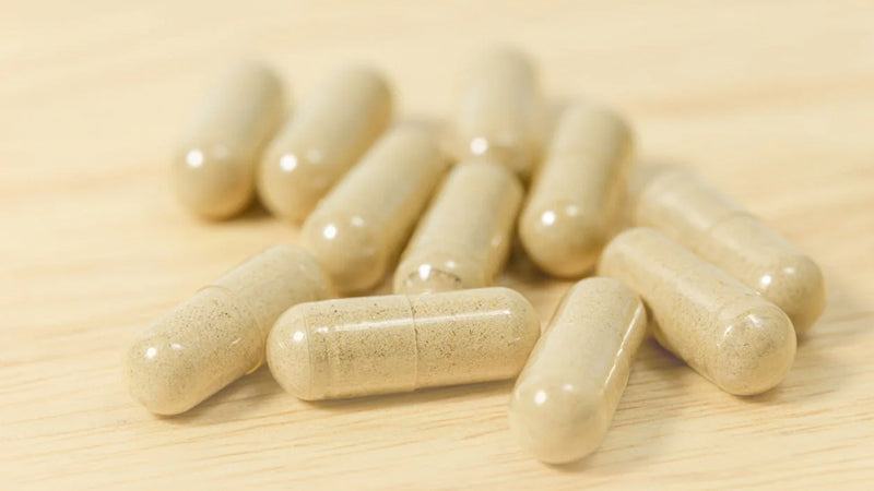 Closeup on a small pile of supplement capsules on a wood surface.