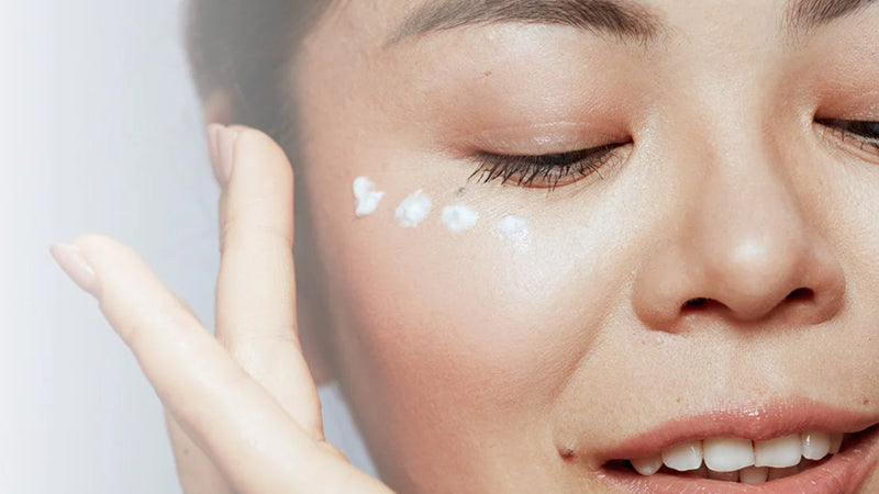 Closeup on a woman applying eye cream under her eyes.