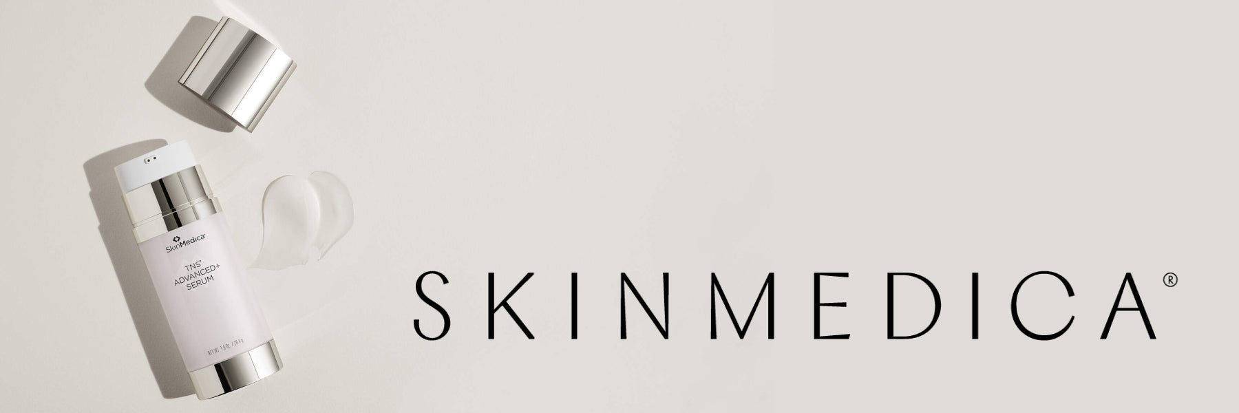 A bottle of SkinMedica TNS Advanced+ Serum lies open next to a small pool of the serum on a beige background, with the SkinMedica logo to the right.