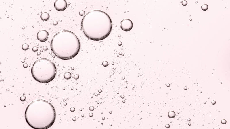 Bubbles in a transparent pink-tinted serum