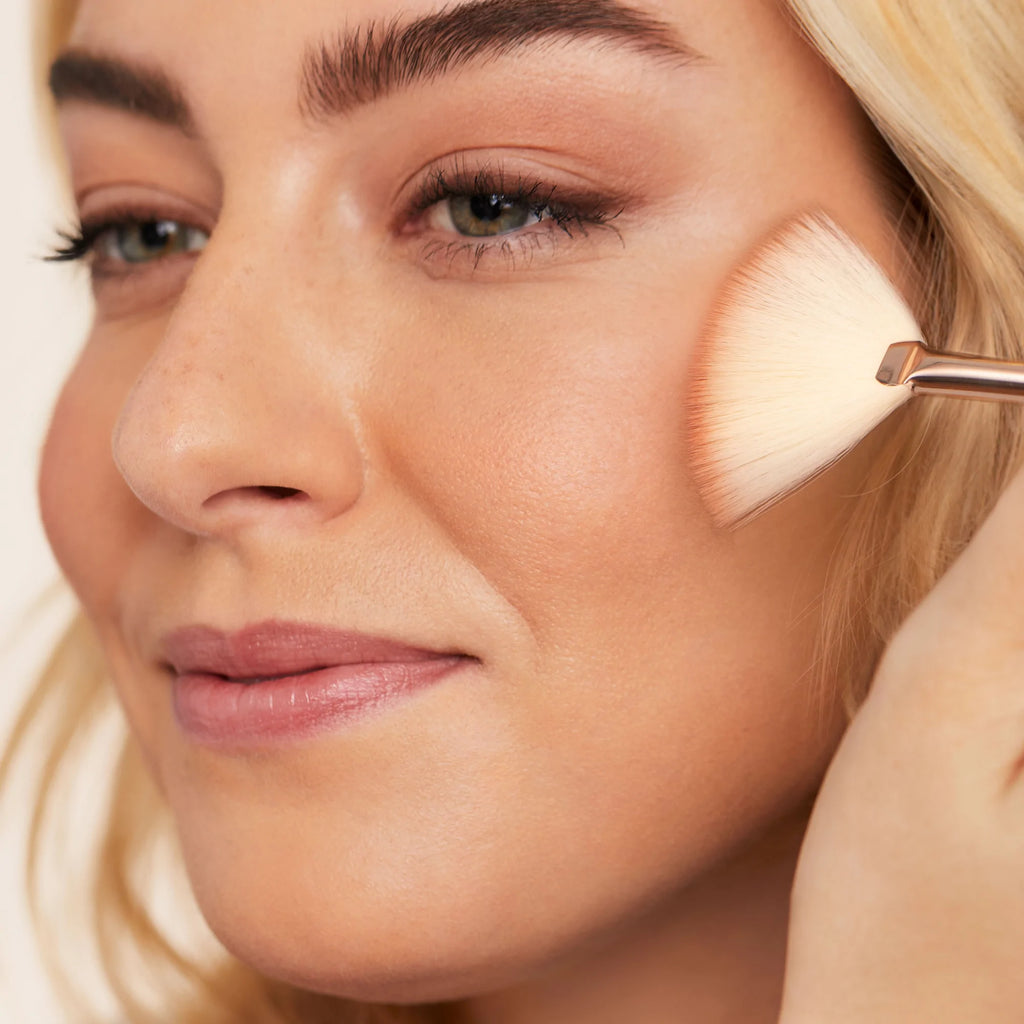 Model applying Jane Iredale Bronzer to cheeck with the fan brush